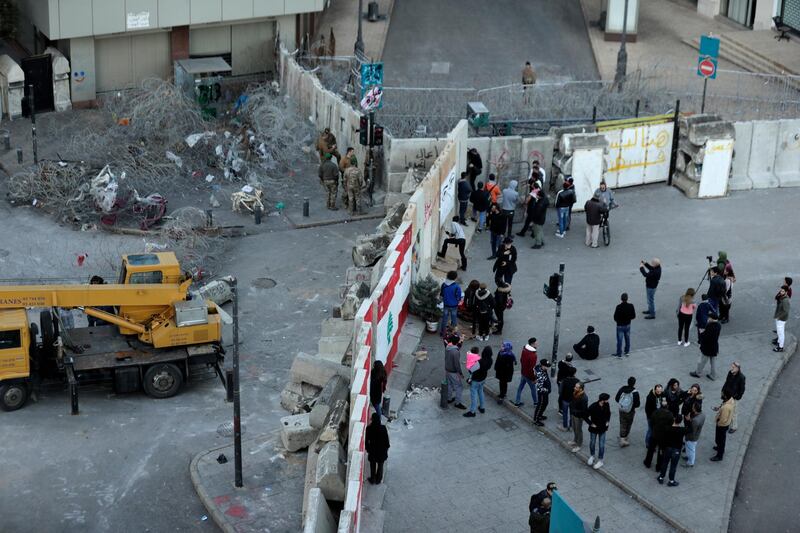 Anti-government protesters protest in front a concrete wall installed by authorities to keep protesters far from the main Lebanese government headquarters and open road to parliament. AP