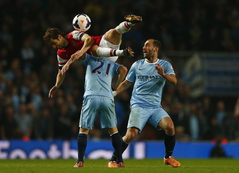 Arsenal’s Mathieu Flamini, left, challenges Manchester City’s David Silva, centre, as Pablo Zabaleta watches during their English Premier League soccer match at The Emirates Stadium in London on March 29, 2014. REUTERS/Eddie Keogh