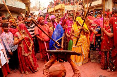 Indian women from Barsana village beat a villager from Nandgoan with wooden sticks as he teases them during Lathmar holi festival celebrations at the legendary hometown of Radha, consort of Hindu god Krishna, in Barsana, India, Tuesday, March 23, 2021. During Lathmar Holi the women of Barsana beat men from Nandgaon, the hometown of Krishna, with wooden sticks in response to their teasing as they depart the town. (AP Photo)