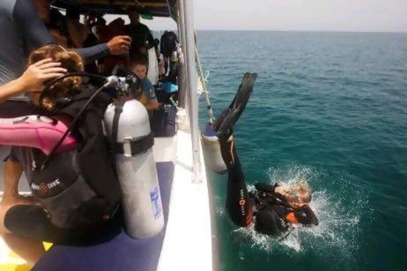 A diver does a back roll into the open water to begin her open water dive at Dibba Rock in Fujairah.