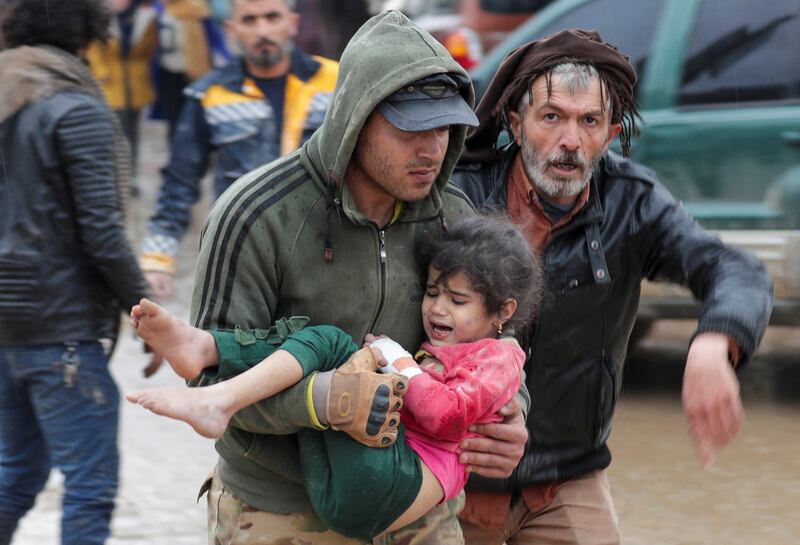 A man carries a girl to safety following the earthquake, in Jandaris, Syria. Reuters