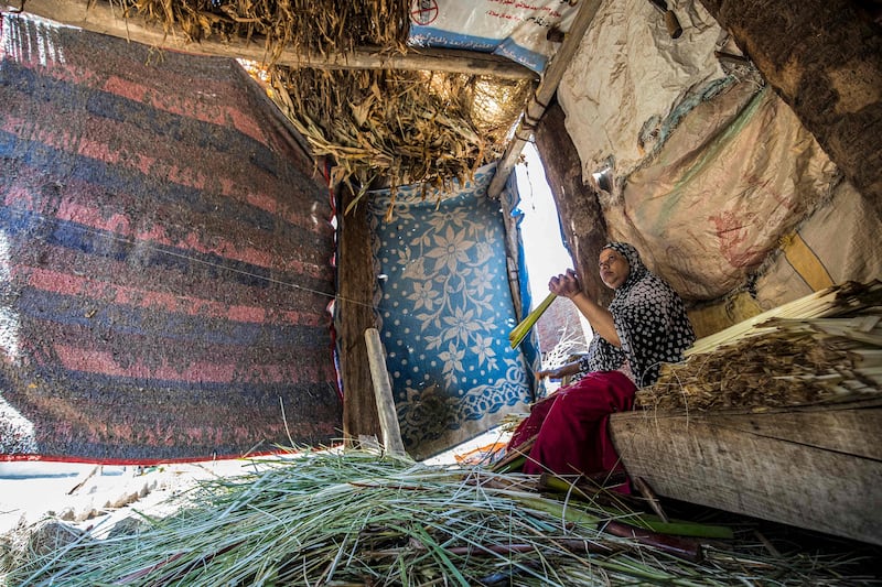 A woman cuts papyrus by a thread at a workshop in the village