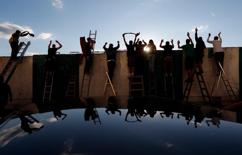 Fans, standing on ladders from behind the fence, celebrate a goal as they watch a Czech first division match between Bohemians Prague and Zlin in Prague, Czech Republic. Amid restrictive measures that limit the number of soccer fans from attending the game, fans are looking for innovative ways to watch the match during the ongoing coronavirus pandemic. AP Photo