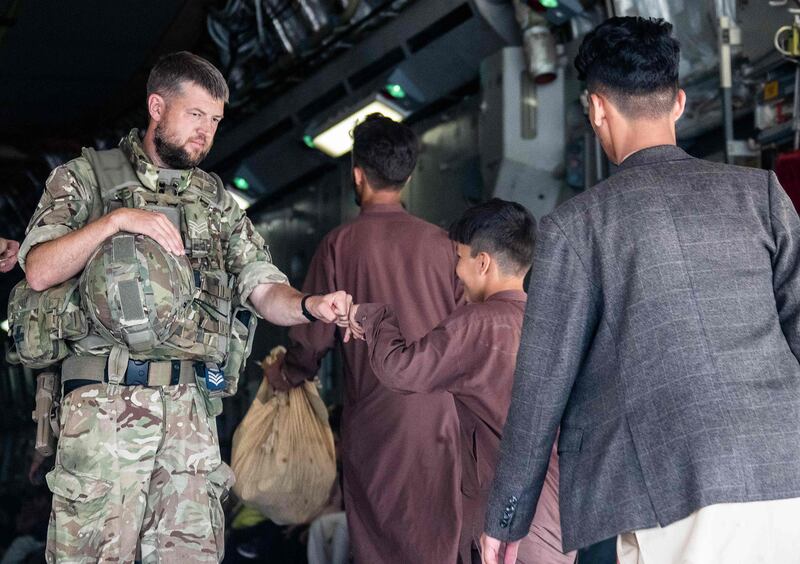 A British soldier fist-bumps a young evacuee at Kabul airport in Afghanistan. Ben Shread / MOD / AFP