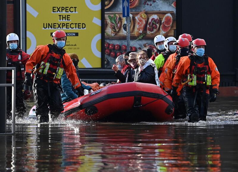 Members of the emergency services evacuate residents in a dinghy . AFP