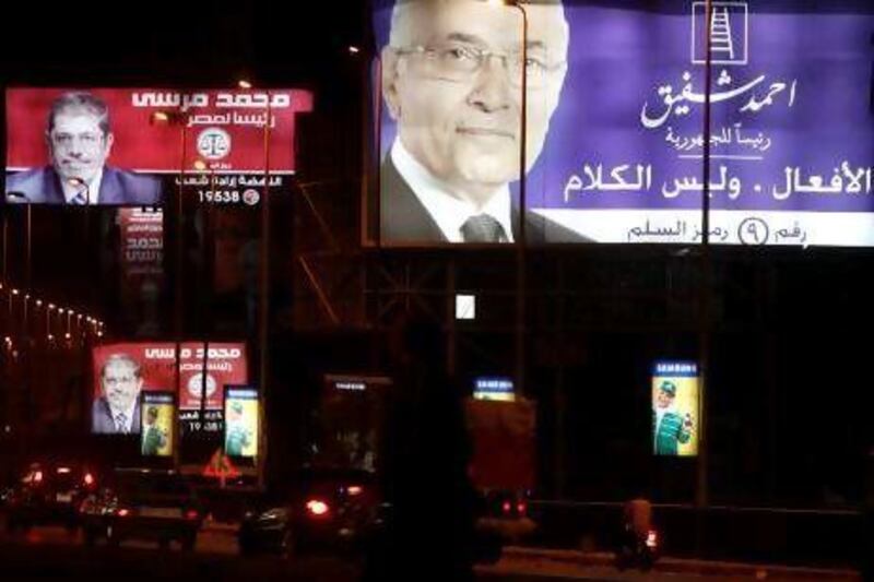 People walk under election billboards of presidential candidates, Ahmed Shafiq, right, and Mohamed Morsi in Cairo.