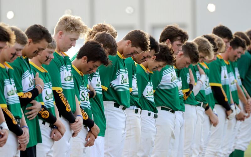 Santa Fe High School baseball players bow their heads in a moment of silence for the shooting victims at their school before a baseball game against Kingwood Park High School in Deer Park, Texas, Saturday, May 19, 2018. A gunman opened fire inside Santa Fe High School Friday, May 18, 2018, killing at least 10 people. (AP Photo/David J. Phillip)