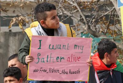 Palestinian hunger-striking prisoner Hisham Abu Hawash's son Ezzeddin lifts a placard during a rally in his village of Dura in the occupied West Bank. AFP