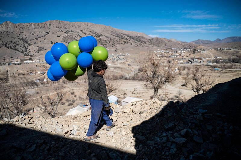 An Afghan boy holds balloons as he walks downhill along a path in Barmal district of Paktika province. AFP