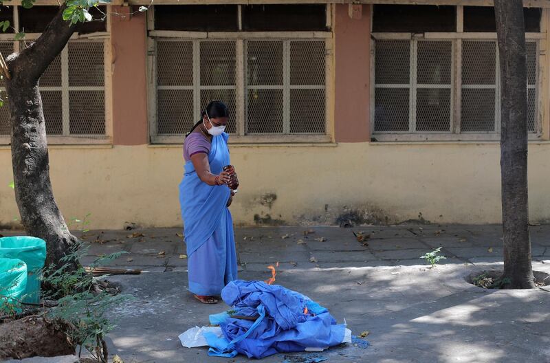 An Indian hospital worker burns used clothes outside of an isolation ward at Fever Hospital in Hyderabad, India. AP Photo