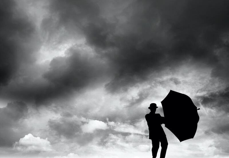 Silhouette of man struggling to hold umbrella