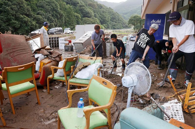 Workers clean a nursing home following a heavy rain in Ashikita town, Kumamoto prefecture. Kyodo News via AP