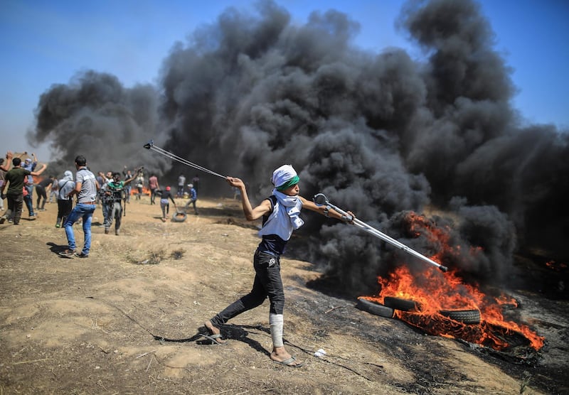 Palestinian protesters hurl stones at Israeli troops during a protest on the Gaza Strip&#39;s border with Israel, Monday, May 14, 2018. On the border with Gaza, at least 58 Palestinians were killed, marking the deadliest day of the demonstrations since late March. Wissam Nassar