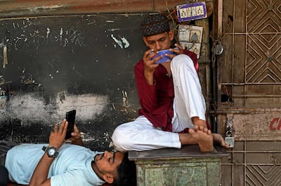 Local residents on their mobile phones in New Delhi. Investcorp is planning to boost its investments in India in sectors including consumer technology. AFP