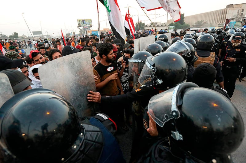 Anti-government protesters gather while Iraqi security prepare to open protesters' site in Basra. AP