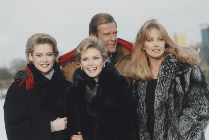 From left to right, actors Alison Doody, Fiona Fullerton, Roger Moore and Tanya Roberts pose at Pinewood Studios in England, to promote the new James Bond film 'A View to a Kill', 1985.  (Photo by Fox Photos/Hulton Archive/Getty Images)