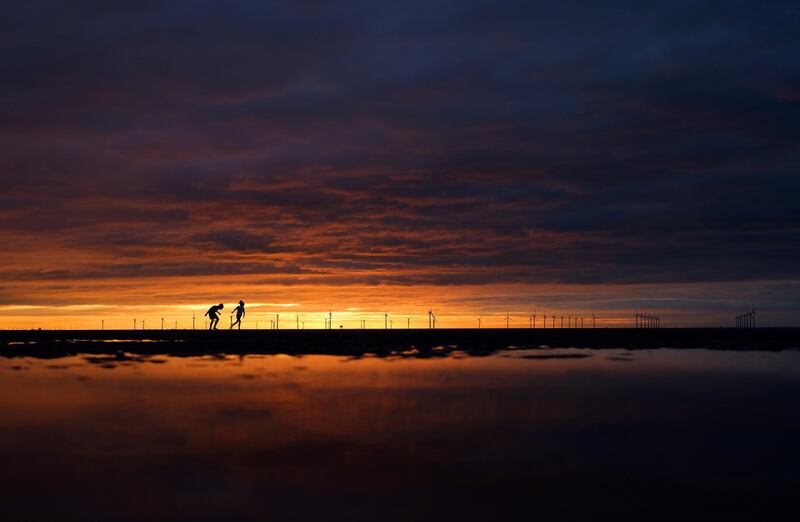 Children run along the beach at sunset in New Brighton, Britain. Reuters