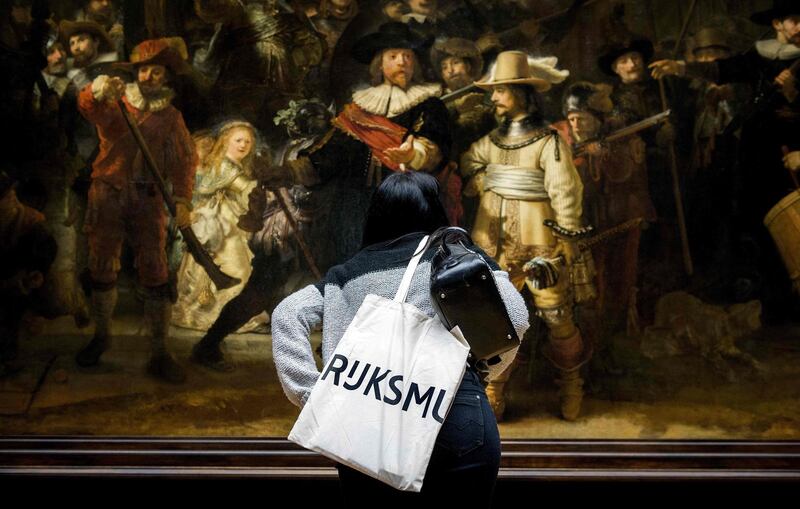 (FILES) In this file photo taken on April 4, 2013, a visitor takes a closer look at Rembrandt's "The Night Watch" during a press-viewing day at the Rijksmuseum in Amsterdam. Amsterdam's famed Rijksmuseum will on July 8, 2019 begin the biggest ever restoration of Rembrandt's "The Night Watch", erecting a huge glass cage around the painting so the public can see the work carried out live. Dubbed "Operation Night Watch", the project is the "largest and most comprehensive research on Rembrandt's masterpiece in history", the museum said in a statement. / AFP / ANP / Koen van Weel
