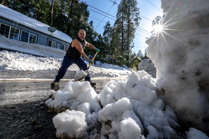 A man clears snow in front of his home in Crestline, California. AP