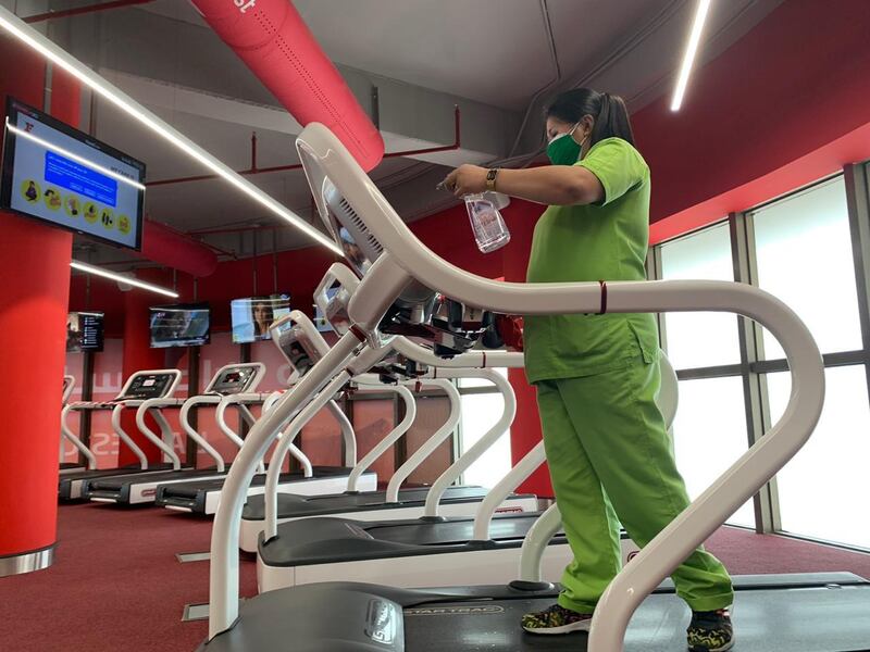 A woman, wearing a protective face mask, sanitises a machine before a training session at a gym in Saudi Arabia's capital Riyadh.   AFP