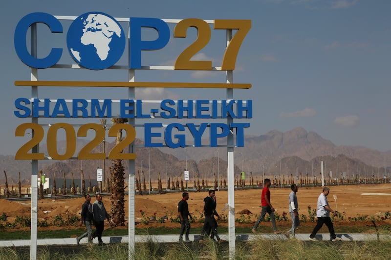Workers walk past signage promoting this year’s United Nations global summit on climate change, known as COP27, adorns Peace Road, in Sharm el-Sheikh, South Sinai, Egypt.  AP Photo