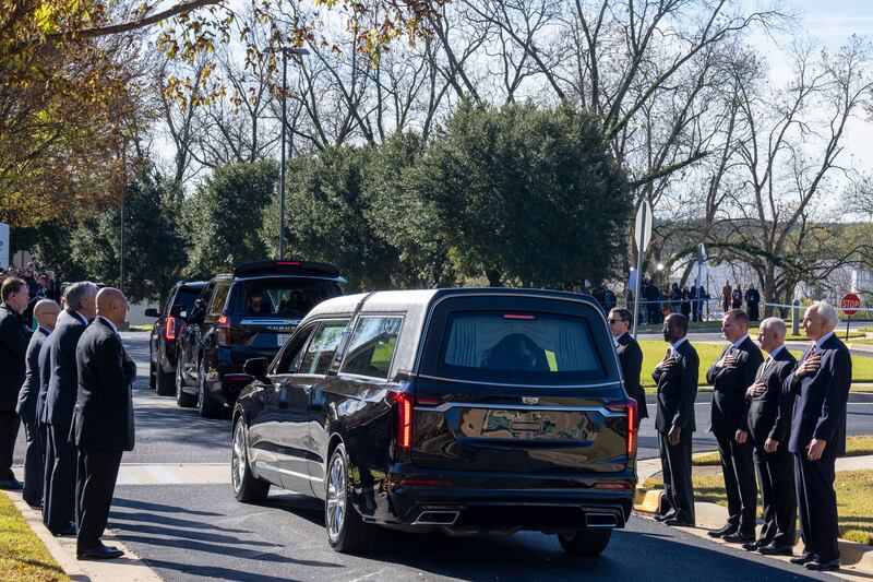 Former and current US Secret Service agents assigned to the Carters stand with their hands over their hearts as the casket departs. AP