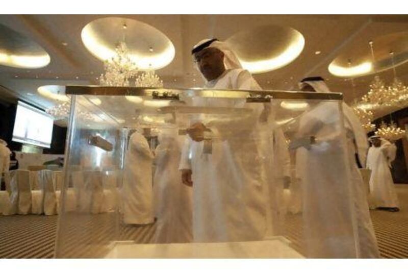 Emirati men check a ballot box for the Federal National Council elections.