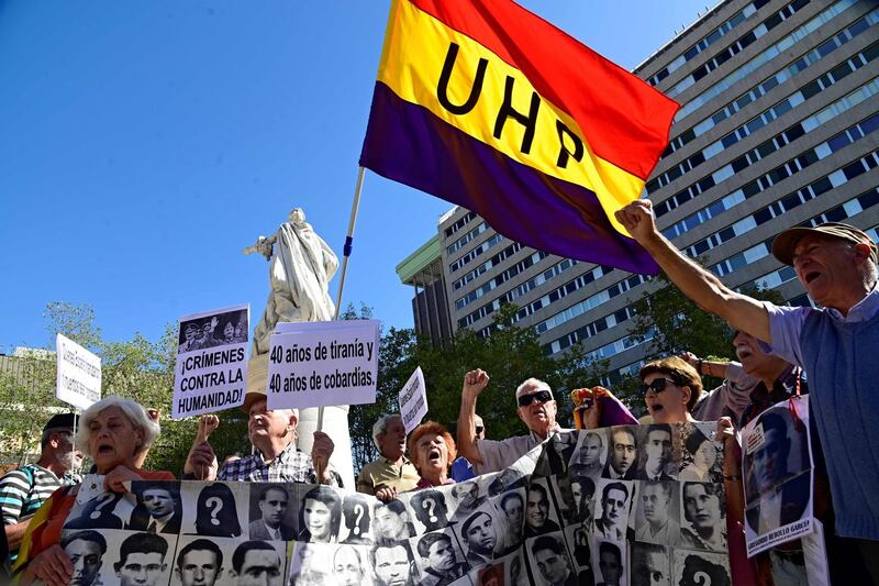 People hold a flag of the Second Spanish Republic and placards reading "Crimes against Humanity" outside the Suprime Court on September 24, 2019 in Madrid, as the court gave the green light for the government to remove the remains of Francisco Franco from a grandiose state mausoleum, rejecting an appeal against it by the late dictator's descendants. / AFP / JAVIER SORIANO
