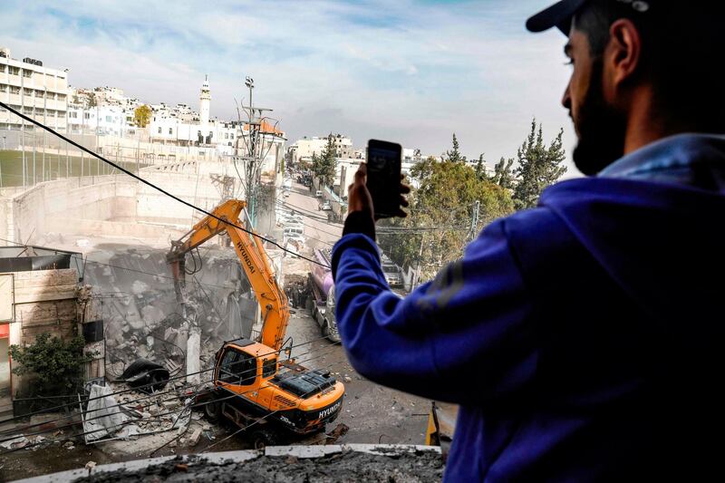 A man films an excavator demolishing one of over a dozen shops in the Arab-inhabited Shuafat refugee camp in East Jerusalem. AFP