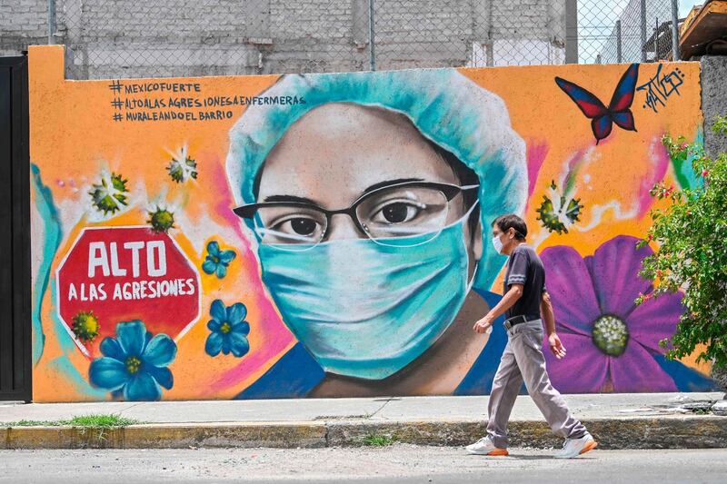 A woman walks past a coronavirus-related mural painted by urban artist Alejandro Bautista Torres, aka Kato, in Mexico City. AFP