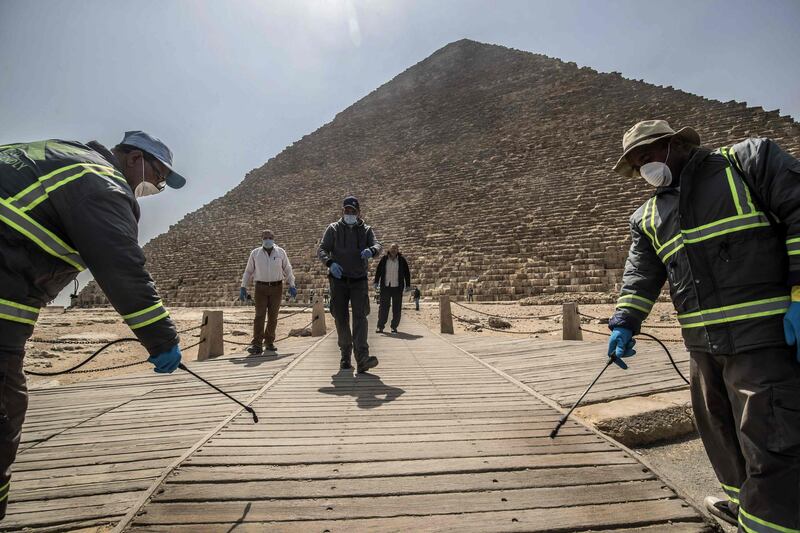 (FILES) In this file photo taken on March 25, 2020 Egyptian municipality workers disinfect the Giza pyramids necropolis on the southwestern outskirts of the Egyptian capital Cairo, as protective a measure against the spread of the coronavirus COVID-19. Hotels have ramped up hygiene, archaeological sites have been sanitised and beaches cleaned up -- Egypt is gearing up to welcome back tourists kept away by the coronavirus pandemic. Egypt has since March halted air traffic and shuttered archaeological sites, museums and hotels to stem the spread of COVID-19. The North African country, like elsewhere, has in recent weeks started loosening confinement measures as it looks to slowly open up to tourists in the summer season.
 / AFP / Khaled DESOUKI
