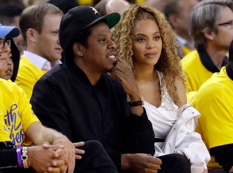 FILE- In this April 28 2018, file photo Jay-Z and Beyonce watch Game 1 of an NBA basketball second-round playoff series between the Golden State Warriors and the New Orleans Pelicans in Oakland, Calif. Police say they are pursuing more charges against a fan who rushed the stage during a Beyonce and Jay Z concert in Atlanta. Atlanta Police officer Lisa Bender told The Associated Press that 26-year-old Anthony Charles Thomas Maxwell ran onto the stage, approached Jay-Z and made contact with him as the concert was ending Saturday night, Aug. 25, 2-18.(AP Photo/Marcio Jose Sanchez, File)