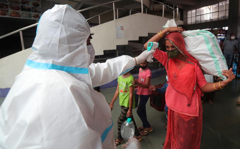 A health worker checks the temperature of a passenger at Bandra train station in Mumbai, India, Wednesday, Feb. 17, 2021. Health officials have detected a spike in COVID-19 cases in several pockets of Maharashtra state, including in Mumbai, the country's financial capital. (AP Photo/Rafiq Maqbool)