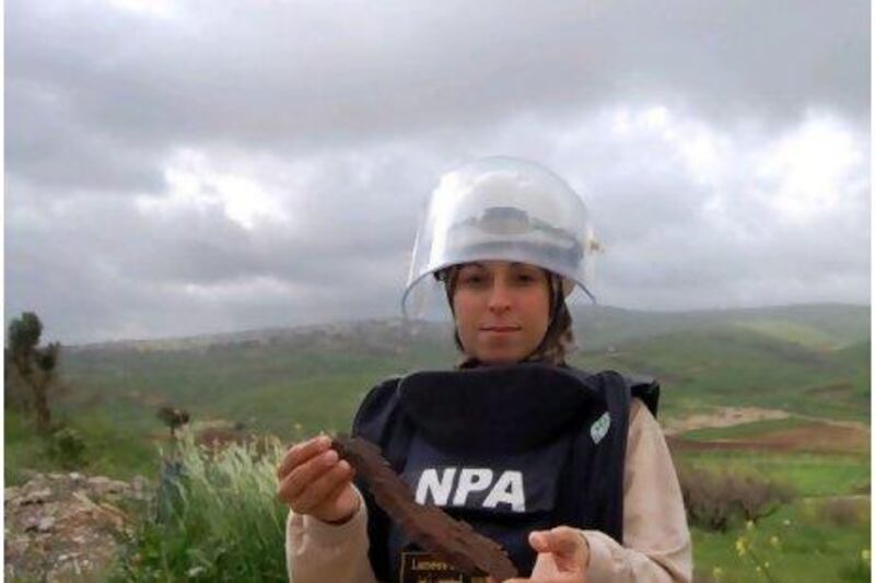 Lebanese mother-of-two Lamis Zein holds a cluster-bomb fragment in Southern Lebanon. Ms Zein said she does the dangerous job because 'I like my country and I want to help'. Courtesy of Norwegian People's Aid