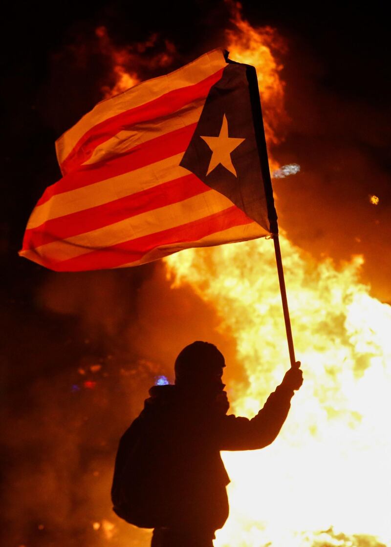 A protester waving a Catalan pro-independence "Estelada" flag stands next to a burning barricade. AFP