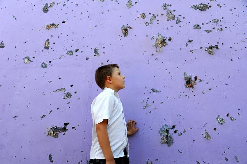 A boy examines holes from shrapnels on a building in the eastern Ukrainian city of Slavyansk, Donetsk region. Viktor Drachev / AFP 