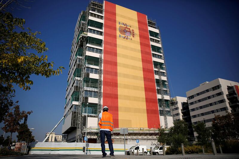 A construction worker looks at a new apartment block draped in a giant Spanish flag in a suburb of Madrid, Spain October 11, 2017. Since Catalonia's attempt to break away from Spain Spanish flags have been displayed on buildings all over Madrid. REUTERS/Andrew Winning     TPX IMAGES OF THE DAY