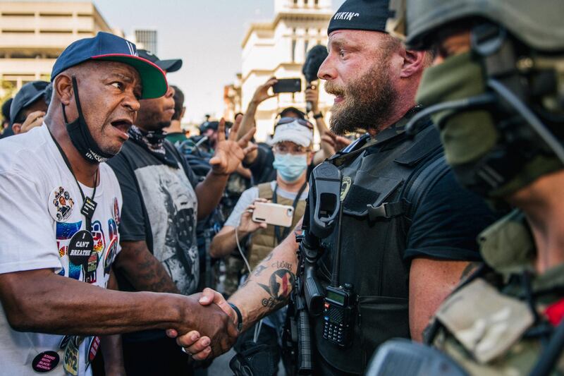 LOUISVILLE, KY - SEPTEMBER 05: A right-wing protester shakes hands with a Black Lives Matter protester in front of the Louisville Metro Hall on September 5, 2020 in Louisville, Kentucky. Ahead of the Kentucky Derby, demonstrators clashed over recent looting and destruction in the area and the death of Breonna Taylor, who was fatally shot by Louisville Metro police officers during a no-knock raid at her apartment on March 13, 2020.   Brandon Bell/Getty Images/AFP