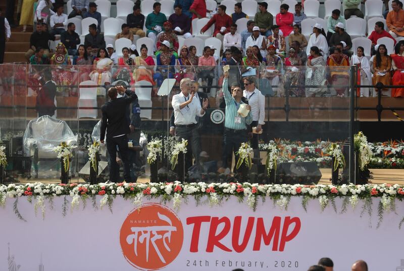 An officer directs workers to clean the glass enclosure erected on the podium where U.S. President Donald Trump and Indian Prime Minister Narendra Modi will be seated at Sardar Patel stadium in Ahmedabad, India. AP Photo