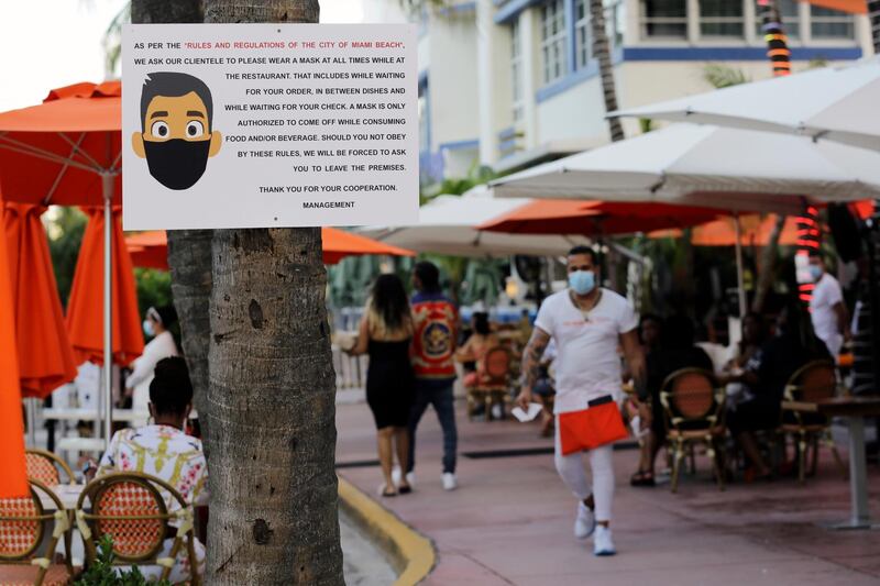 A sign informs customers at the Edison Hotel restaurant about wearing a protective face mask during the coronavirus pandemic, along Ocean Drive in Miami Beach, Florida, USA. AP Photo