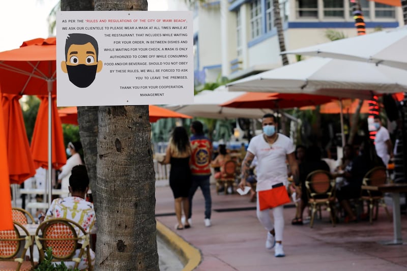 A sign informs customers at the Edison Hotel restaurant about wearing a protective face mask during the coronavirus pandemic, along Ocean Drive in Miami Beach, Florida, USA. AP Photo