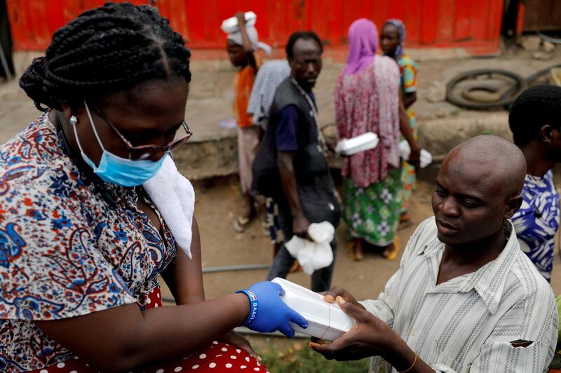 FILE PHOTO: A volunteer distributes cooked food and water to the underprivileged and homeless, as Ghana enforces a partial lockdown in Accra and Kumasi in efforts to slow the spread of the coronavirus disease (COVID-19), in Accra, Ghana. April 4, 2020. REUTERS/Francis Kokoroko/File Photo