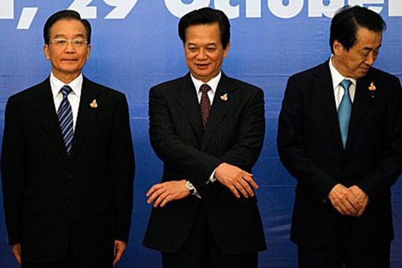 Nguyen Tan Dung, centre, Vietnam's prime minister, reaches hands towards the Japanese prime minister Naoto Kan, right, and China's premier Wen Jiabao at the start of the 13th Asean Plus Three Summit in Hanoi yesterday.