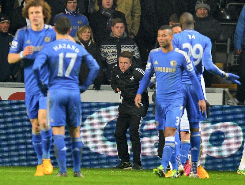 A ball boy (C) picks himself up off the ground after being involved in an altercation with Chelsea's Belgium midfielder Eden Hazard during the English League Cup semi-final second leg football match between Swansea City and Chelsea at The Liberty stadium in Cardiff, south Wales on January 23, 2013. Hazard was sent off after the incident.  AFP PHOTO/ANDREW YATES

RESTRICTED TO EDITORIAL USE. No use with unauthorized audio, video, data, fixture lists, club/league logos or “live” services. Online in-match use limited to 45 images, no video emulation. No use in betting, games or single club/league/player publications. (Photo by ANDREW YATES / AFP)