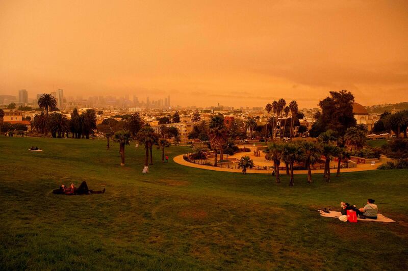 People relax under an orange smoke-filled sky at Dolores Park in San Francisco, California.  AFP