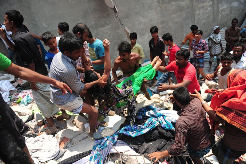 Bangladeshi garment workers help evacuate a survivor after an eight-storey building collapsed in Savar, on the outskirts of Dhaka, on April 24, 2013. At least 60 people were killed and many more feared dead when an eight-storey building housing a market and garment factory collapsed in Bangladesh on Wednesday, an official said.  AFP PHOTO/Munir uz ZAMAN
 *** Local Caption ***  978794-01-08.jpg