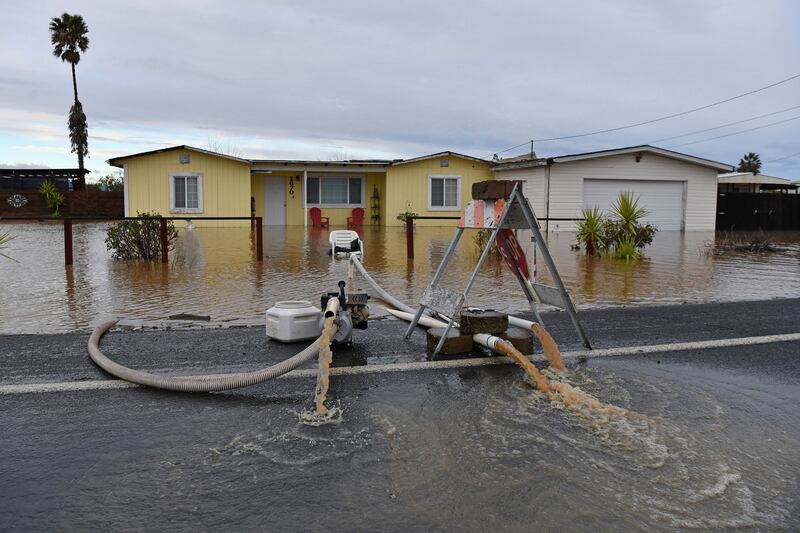 A resident attempts to pump the water from around his home in Brentwood. AP