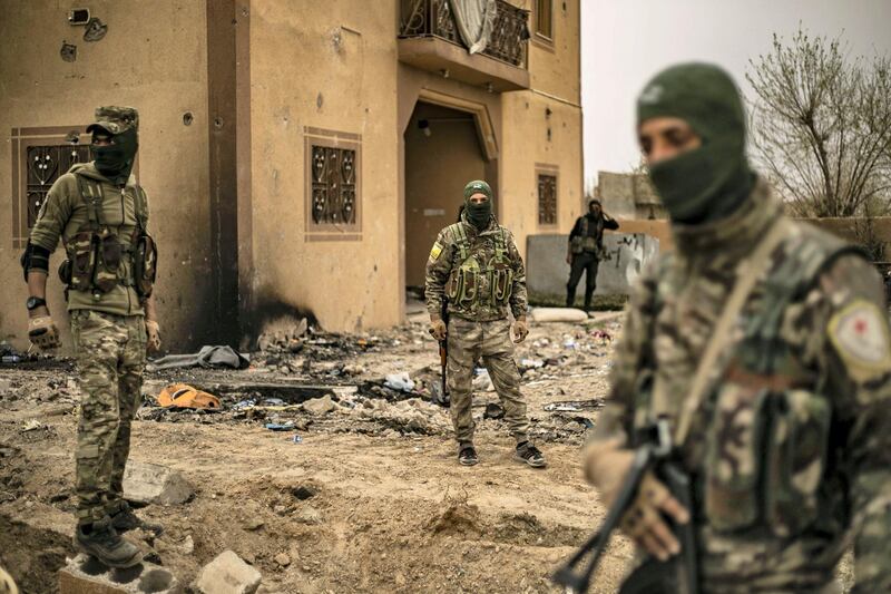 EDITORS NOTE: Graphic content / Members of the Syrian Democratic Forces (SDF) walk in the village of Baghouz in Syria's eastern Deir Ezzor province near the Iraqi border on March 24, 2019, a day after the Islamic State (IS) group's "caliphate" was declared defeated by the US-backed Kurdish-led SDF. (Photo by Delil souleiman / AFP)