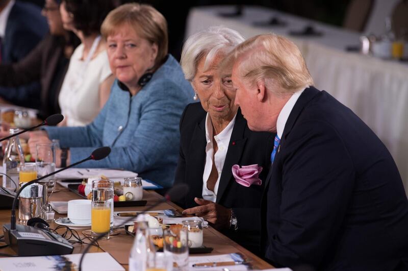 US President Donald Trump speaks to International Monetary Fund Managing Director Christine Lagarde at the Gender Equality Advisory Council Breakfast as German Chancellor Angela Merkel looks on.  Saul Loeb / AFP