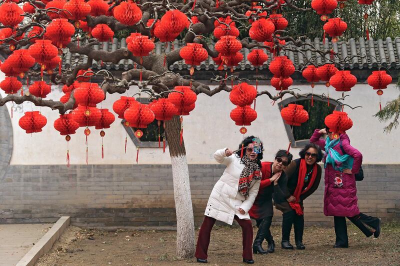 Chinese women take a selfie near a tree decorated with red lanterns. AP Photo